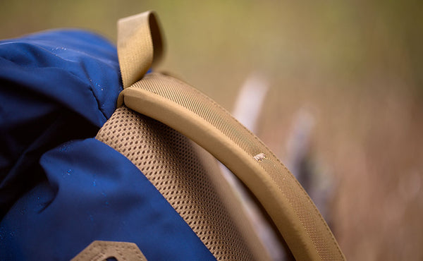 A close shot of the seam attaching the nylon grab handle, backpack straps, and top pocket of the Guide's Pack.